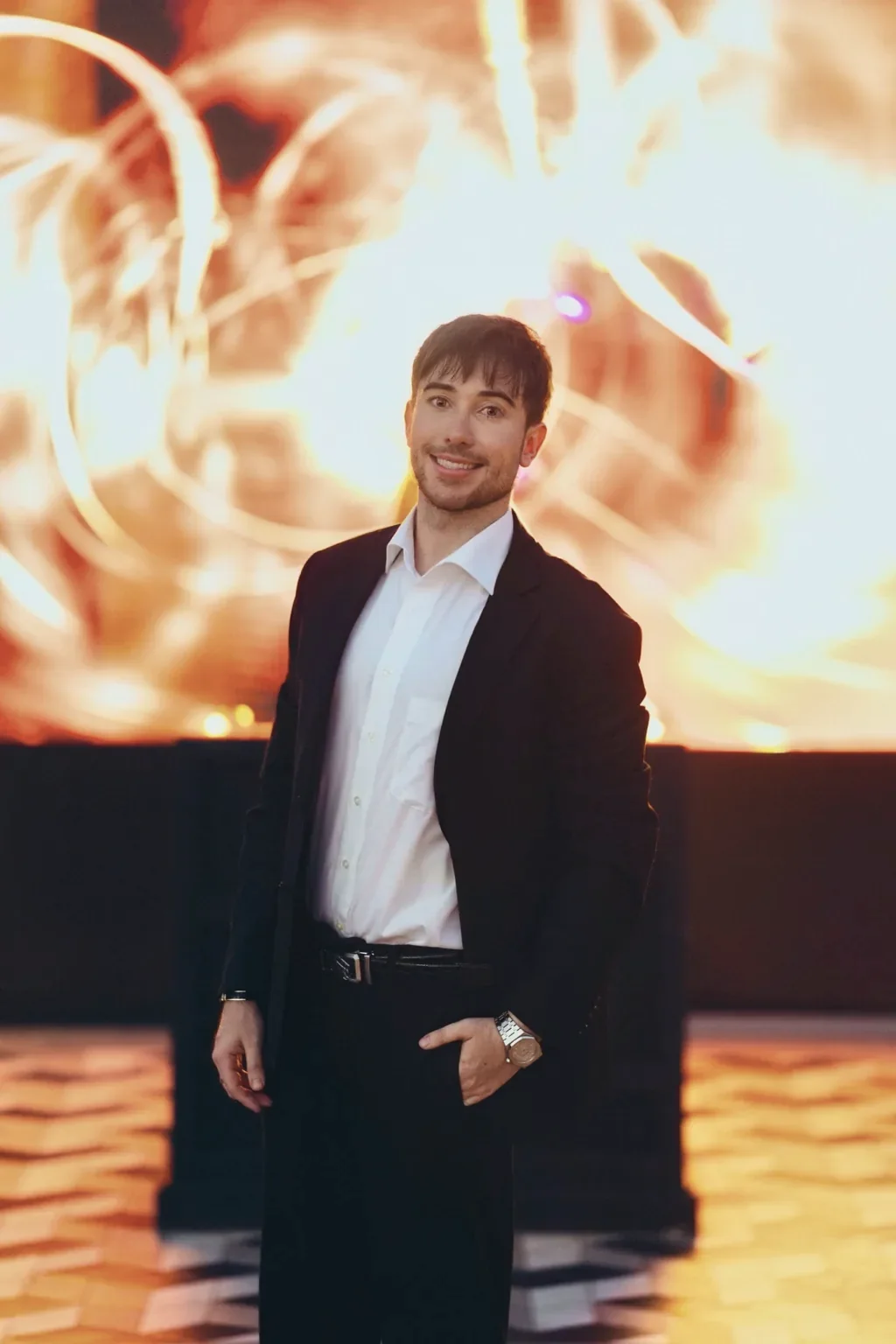 Alexander Weiskopf in a dark suit in front of warm, abstract light