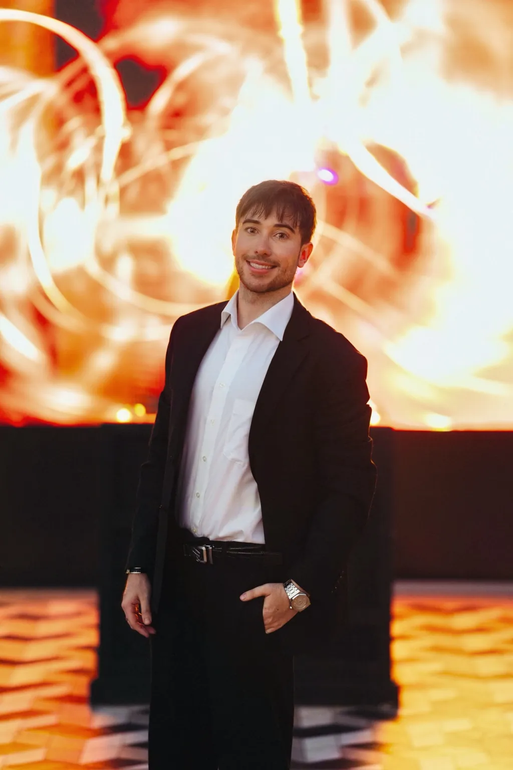 Alexander Weiskopf in a dark suit in front of warm, abstract light